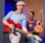 Blippi is playing an electric guitar, Meekah is holding a ukulele, both smiling happily.
