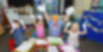 Blippi and three children playing in the classroom, "ABCDE" board.